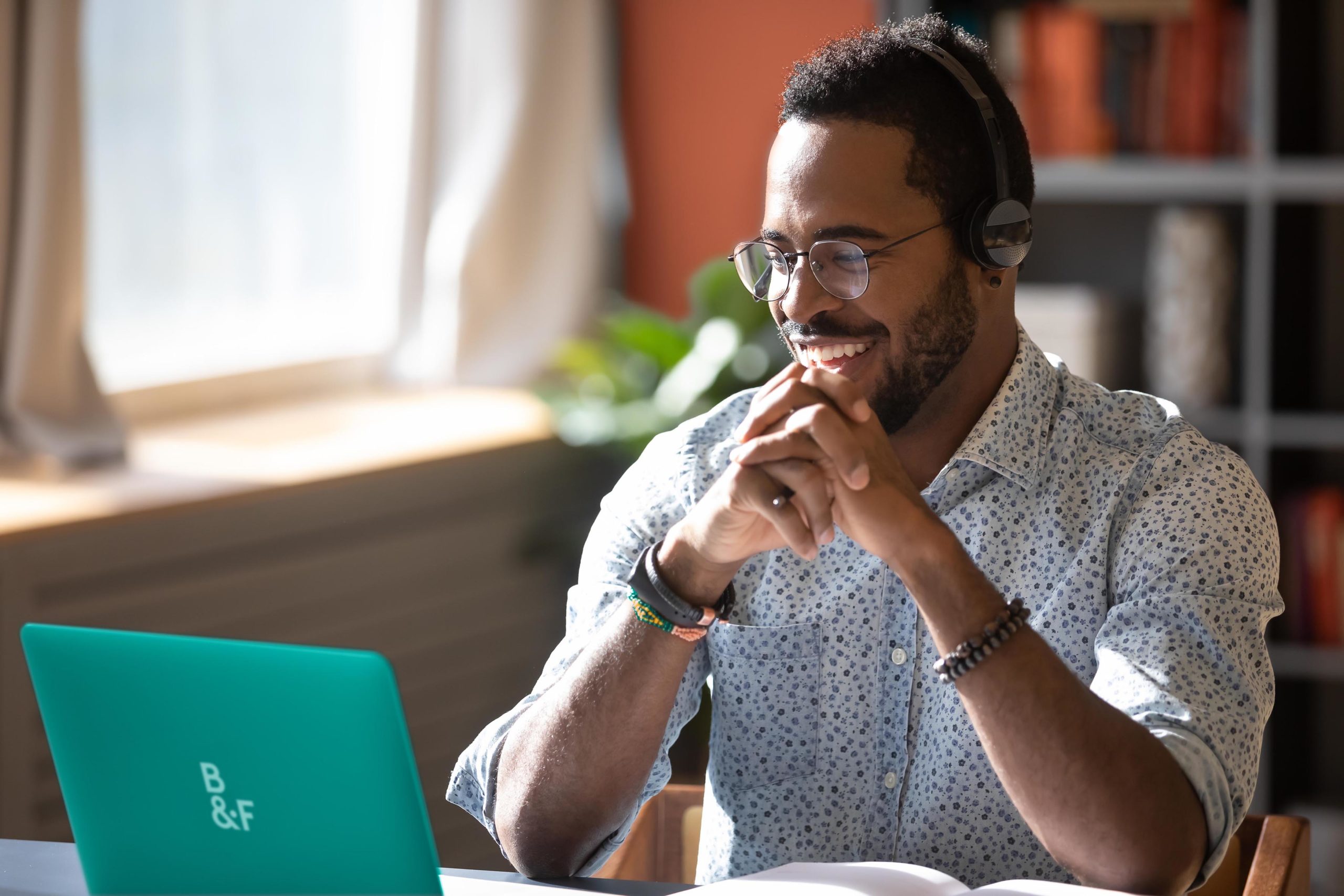 A happy guy looking at his laptop with headphones on