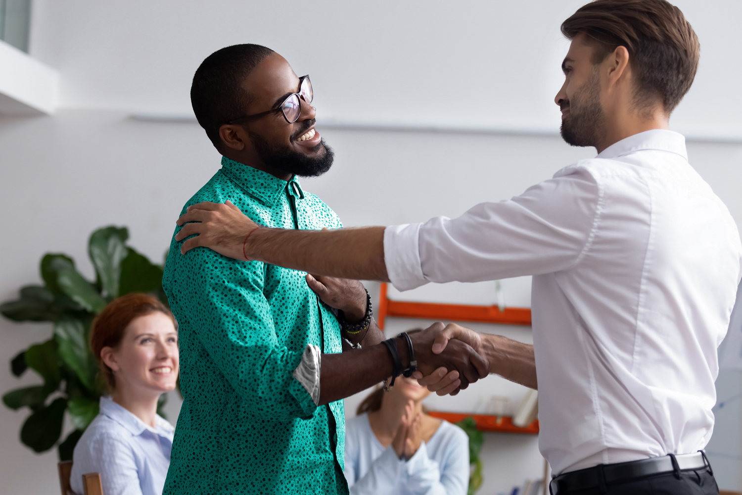 Diverse people gathered in meeting executive manager shake hands with black employee impressed by professionalism for leadership qualities creative solutions and efforts rewarding him for amazing work