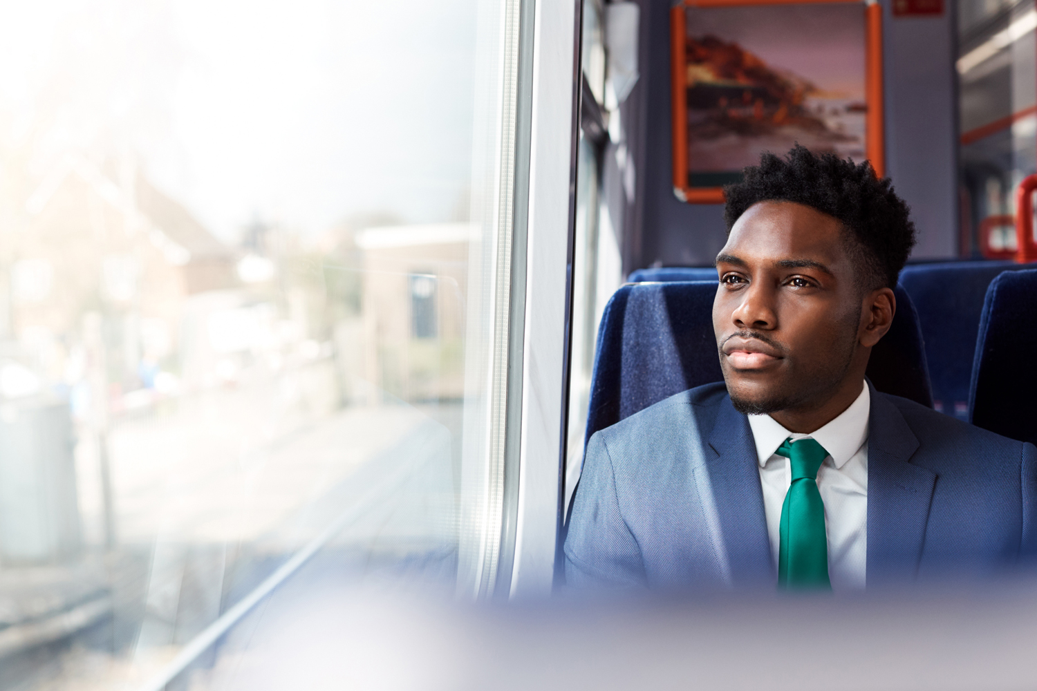 Businessman Sitting In Train Commuting To Work Looking Out Of Window