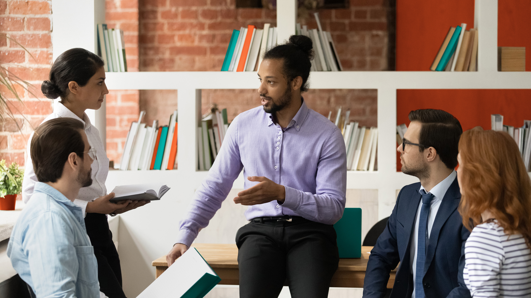 Concentrated young serious african american boss mentor leading brainstorming meeting with multiracial diverse colleagues in modern office, discussing corporate growth strategy or business issues.