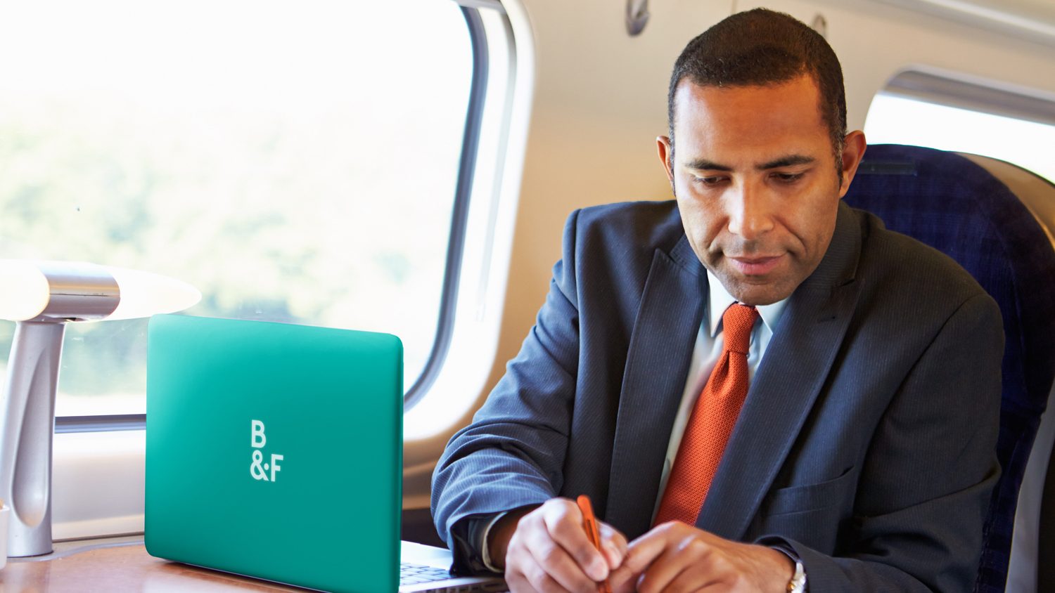 Businessman Commuting To Work On Train And Using Laptop