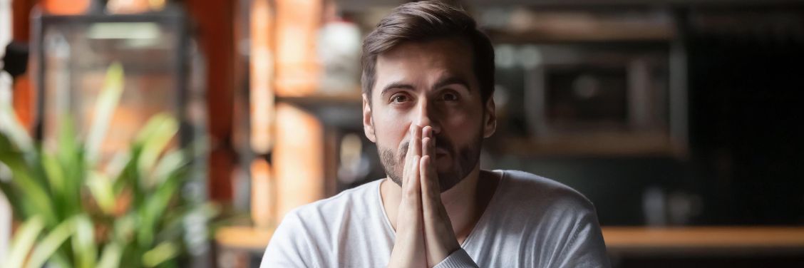A person looking into the distance thinking with their hands up by their face